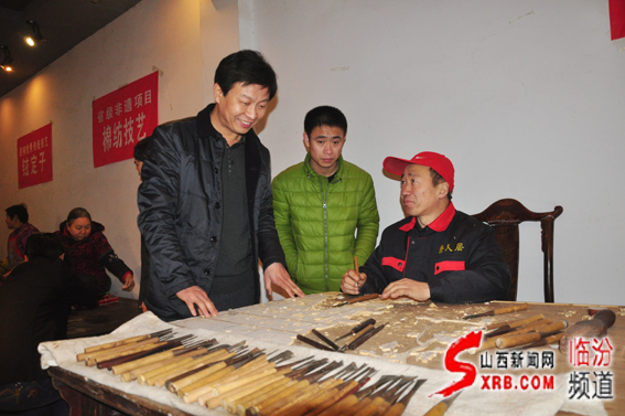 03、臨汾市非物質(zhì)文化遺產(chǎn)主任任江波（左一）在向制作師傅了解晉作家具制作雕刻技藝